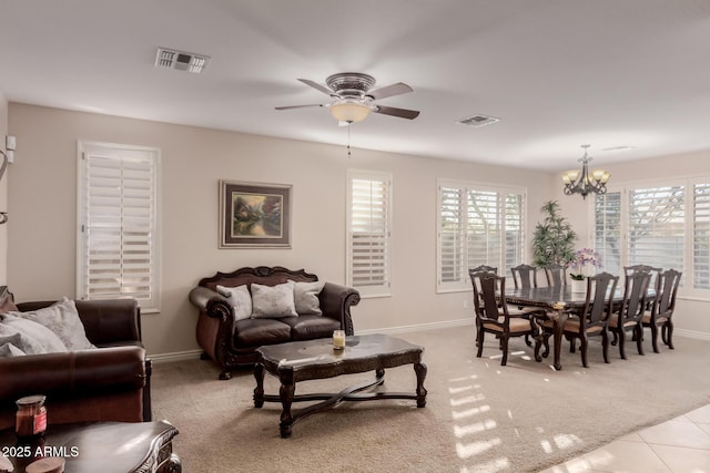 carpeted living room featuring ceiling fan with notable chandelier