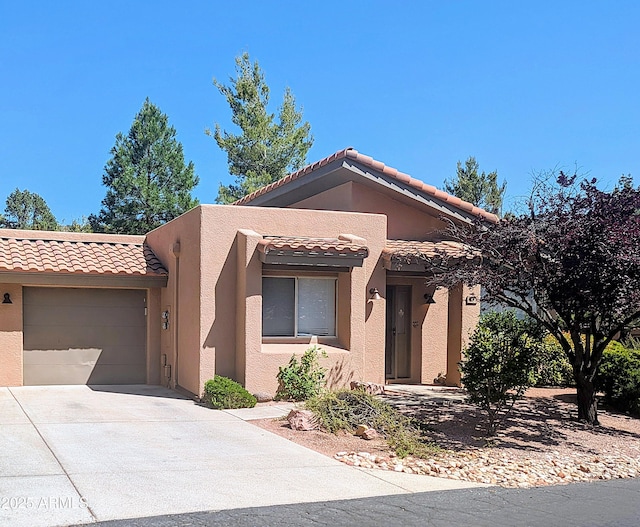 view of front of house with a tile roof, driveway, a garage, and stucco siding