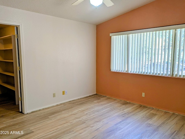 unfurnished room featuring vaulted ceiling, wood finished floors, ceiling fan, and baseboards