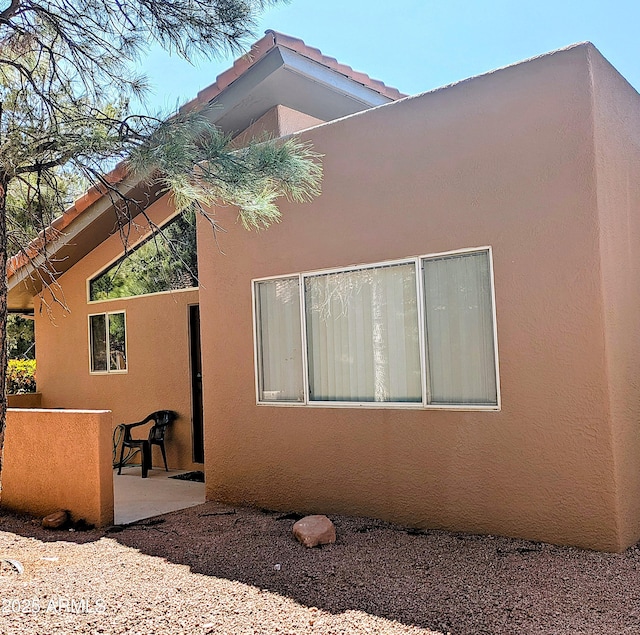 view of property exterior with stucco siding and a patio