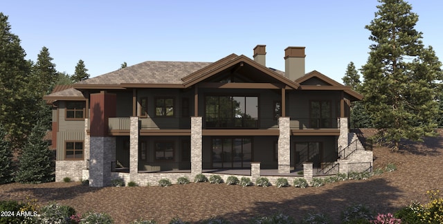 rear view of property with a patio area, a chimney, stone siding, and a balcony
