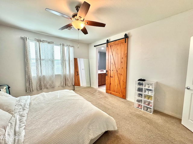 carpeted bedroom featuring ceiling fan, connected bathroom, and a barn door