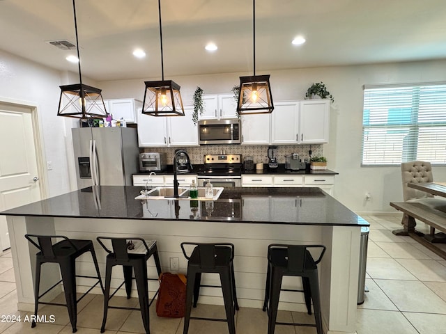 kitchen with stainless steel appliances, white cabinets, decorative light fixtures, and a breakfast bar area