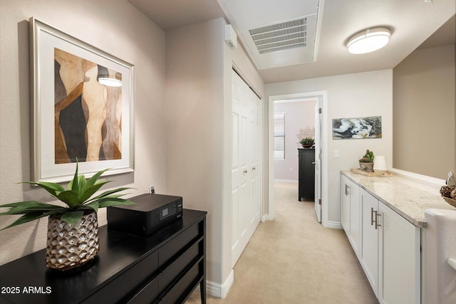 hall featuring baseboards, visible vents, and light colored carpet