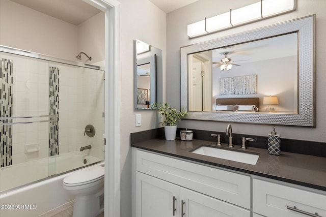 bathroom with bath / shower combo with glass door, vanity, toilet, and a ceiling fan