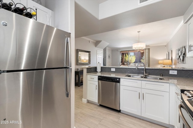 kitchen featuring light stone counters, a peninsula, a sink, white cabinetry, and appliances with stainless steel finishes