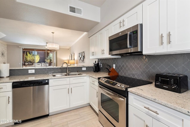 kitchen featuring stainless steel appliances, a sink, visible vents, white cabinets, and hanging light fixtures