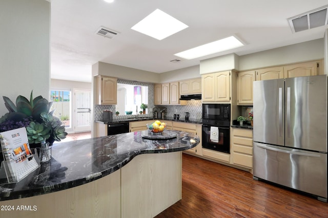 kitchen featuring black appliances, dark stone countertops, dark hardwood / wood-style flooring, kitchen peninsula, and backsplash