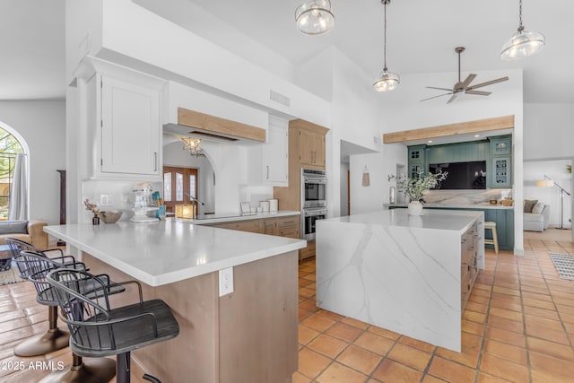 kitchen featuring a peninsula, a center island, visible vents, stainless steel double oven, and ceiling fan