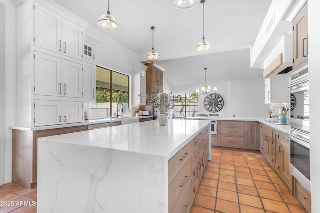kitchen featuring a center island, hanging light fixtures, a sink, white cabinets, and light stone countertops