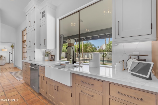 kitchen with white cabinets, light stone countertops, a sink, and light tile patterned floors