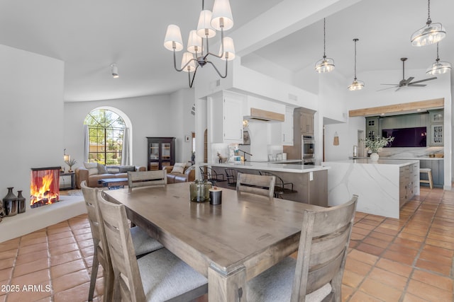 dining room with lofted ceiling, visible vents, a ceiling fan, a multi sided fireplace, and light tile patterned floors