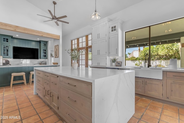 kitchen featuring a center island, a sink, open floor plan, glass insert cabinets, and a ceiling fan