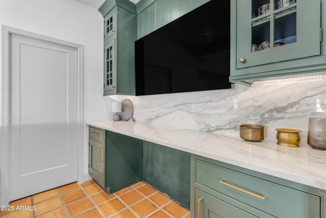 kitchen with tasteful backsplash, light stone countertops, and green cabinets