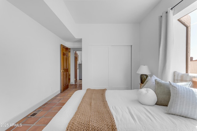 tiled bedroom featuring baseboards, visible vents, a closet, and multiple windows