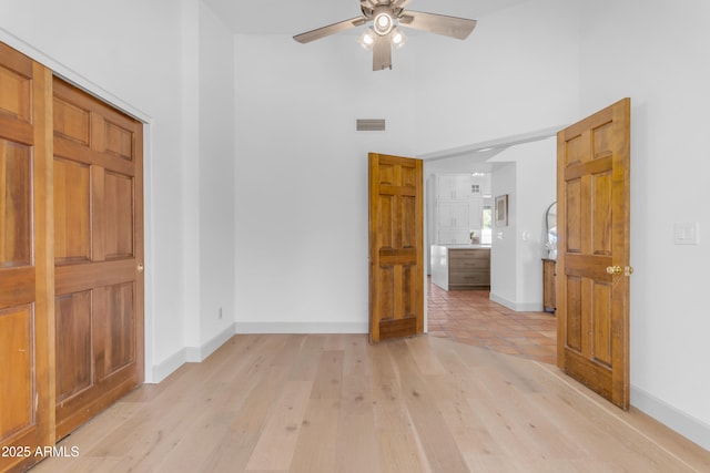 unfurnished bedroom with a high ceiling, baseboards, and visible vents