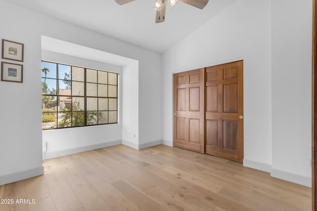 unfurnished bedroom with ceiling fan, baseboards, lofted ceiling, and light wood-style flooring