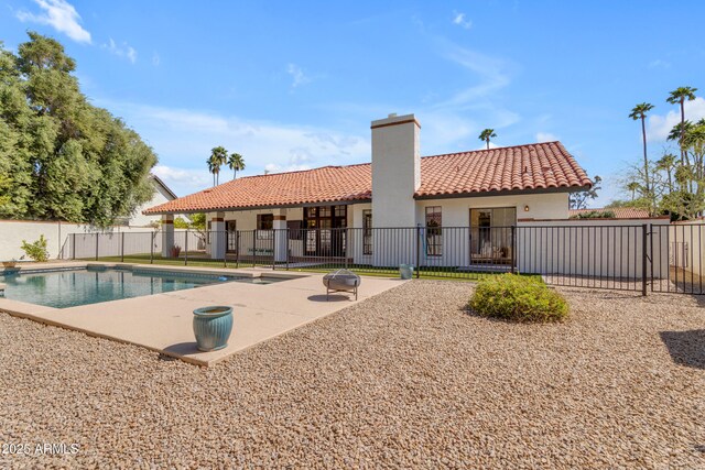 rear view of house featuring a tiled roof, a chimney, fence, a patio area, and stucco siding
