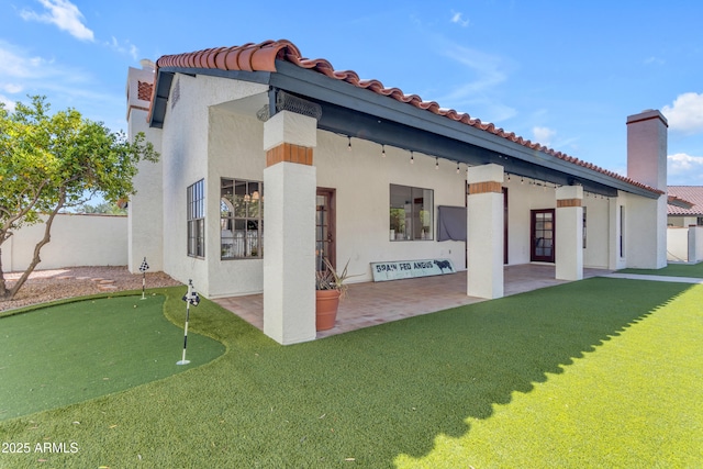 rear view of property with a chimney, a tiled roof, fence, a patio, and stucco siding