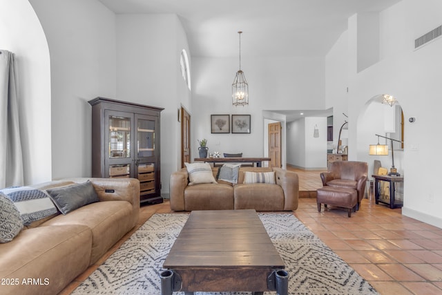 living area featuring a high ceiling, visible vents, arched walkways, baseboards, and a chandelier