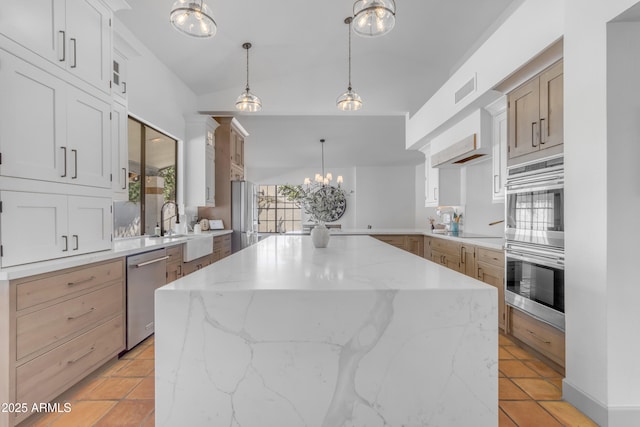 kitchen with light stone counters, stainless steel appliances, visible vents, a sink, and a kitchen island