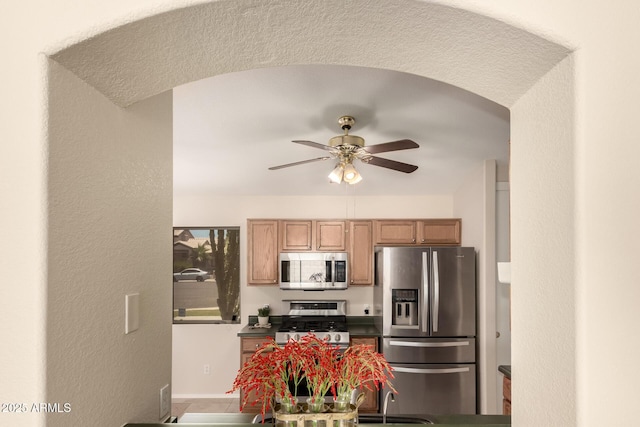 16288 W Hadley St, Goodyear, AZ 85338 - kitchen with appliances with stainless steel finishes, a ceiling fan, dark countertops, and arched walkways