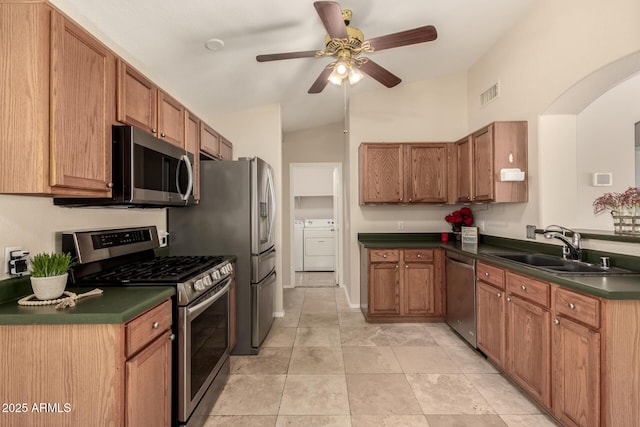 16288 W Hadley St, Goodyear, AZ 85338 - kitchen with appliances with stainless steel finishes, washing machine and dryer, dark countertops, and brown cabinetry