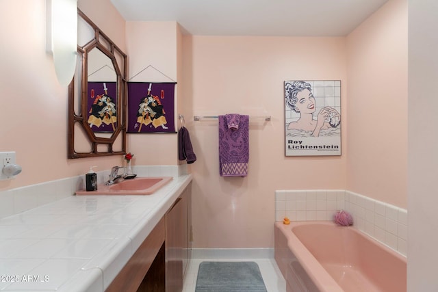 bathroom with vanity, tile patterned floors, a bath, and baseboards