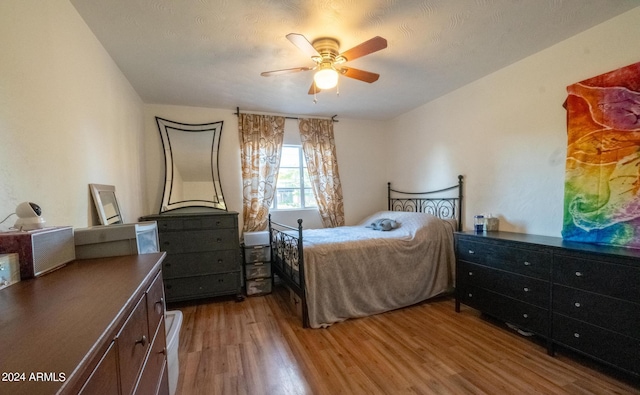 bedroom featuring ceiling fan, hardwood / wood-style flooring, and a textured ceiling