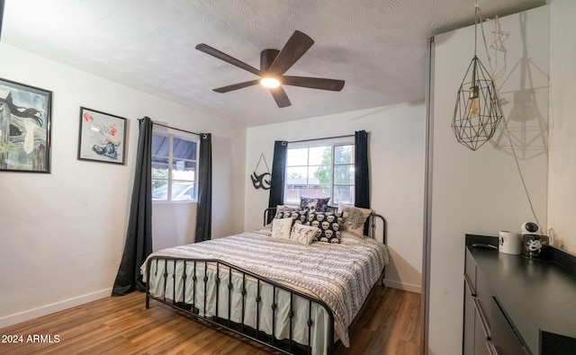 bedroom with a textured ceiling, ceiling fan, and hardwood / wood-style flooring