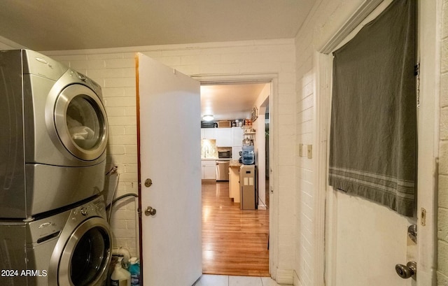 washroom with light wood-type flooring and stacked washer / drying machine