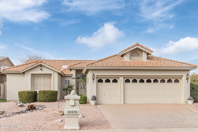 view of front of home with a tiled roof, stucco siding, driveway, and an attached garage