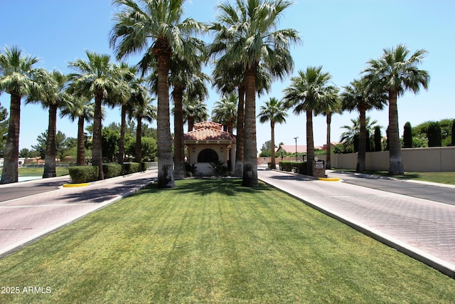 view of front of property featuring stucco siding, a tile roof, a front yard, and fence