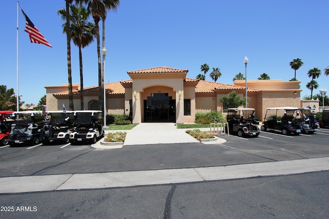 view of front of house featuring stucco siding, a tile roof, and uncovered parking