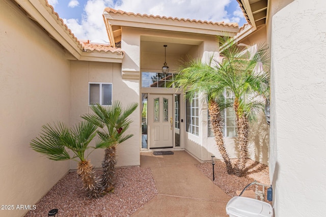 property entrance with stucco siding and a tile roof