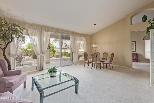 carpeted living area featuring a notable chandelier, baseboards, and high vaulted ceiling