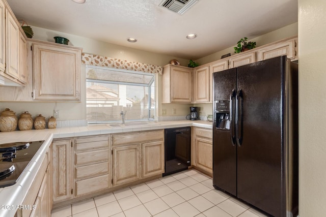 kitchen featuring light brown cabinets, black appliances, and a sink