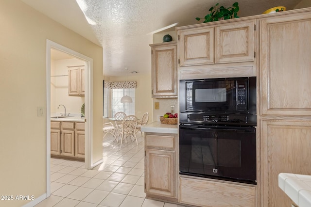 kitchen with black appliances, light brown cabinets, a sink, a textured ceiling, and light tile patterned floors