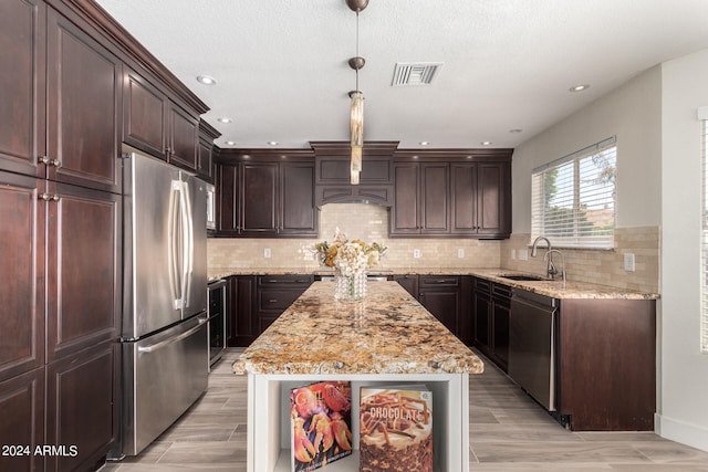 kitchen with light hardwood / wood-style flooring, a center island, sink, light stone countertops, and appliances with stainless steel finishes