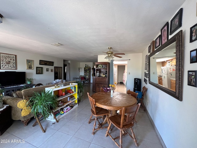 tiled dining area with ceiling fan and a textured ceiling