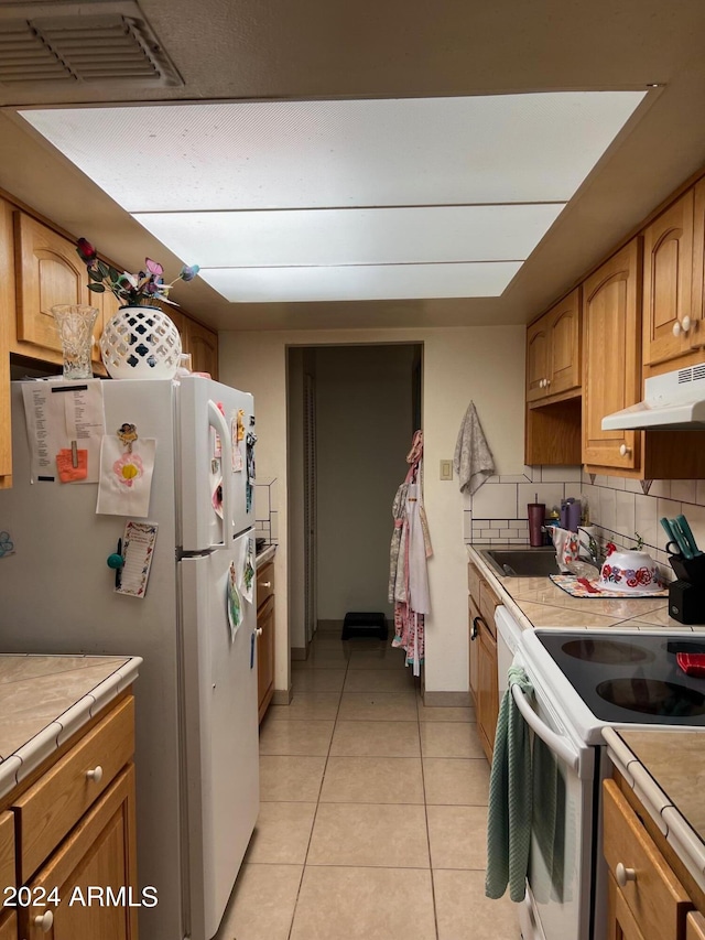 kitchen featuring decorative backsplash, white appliances, tile countertops, and light tile patterned flooring