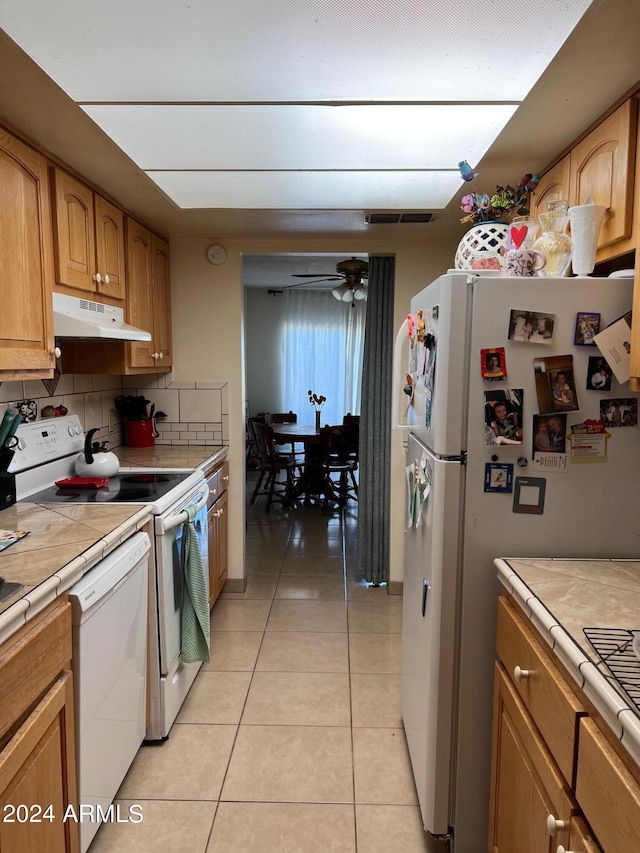 kitchen with ceiling fan, light tile patterned floors, white appliances, tile countertops, and decorative backsplash