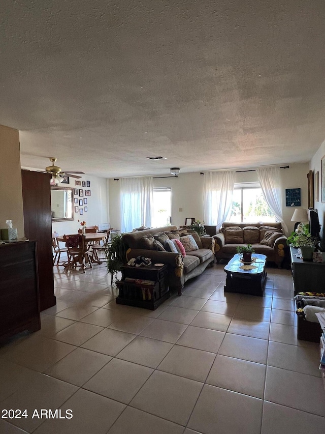 tiled living room featuring ceiling fan and a textured ceiling