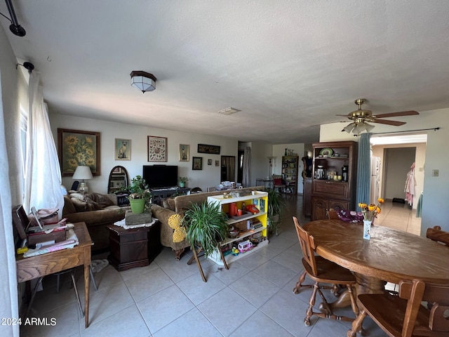 tiled dining area with a textured ceiling and ceiling fan