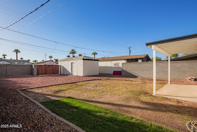 view of yard with an outbuilding, a fenced backyard, a shed, and a patio