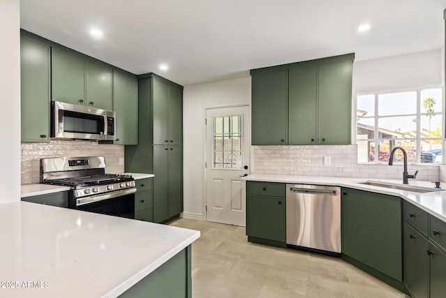 kitchen with a sink, appliances with stainless steel finishes, green cabinets, and a healthy amount of sunlight