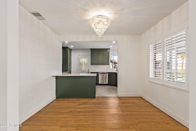 kitchen featuring visible vents, a peninsula, light countertops, stainless steel dishwasher, and light wood-type flooring