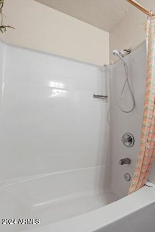 bathroom with shower / bath combo and a textured ceiling