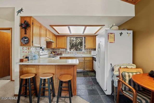 kitchen with tasteful backsplash, white refrigerator, kitchen peninsula, stove, and a breakfast bar area