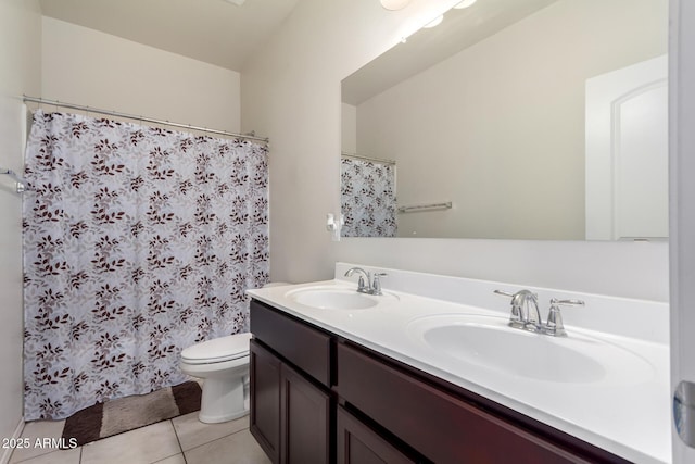 bathroom with double vanity, toilet, tile patterned flooring, and a sink